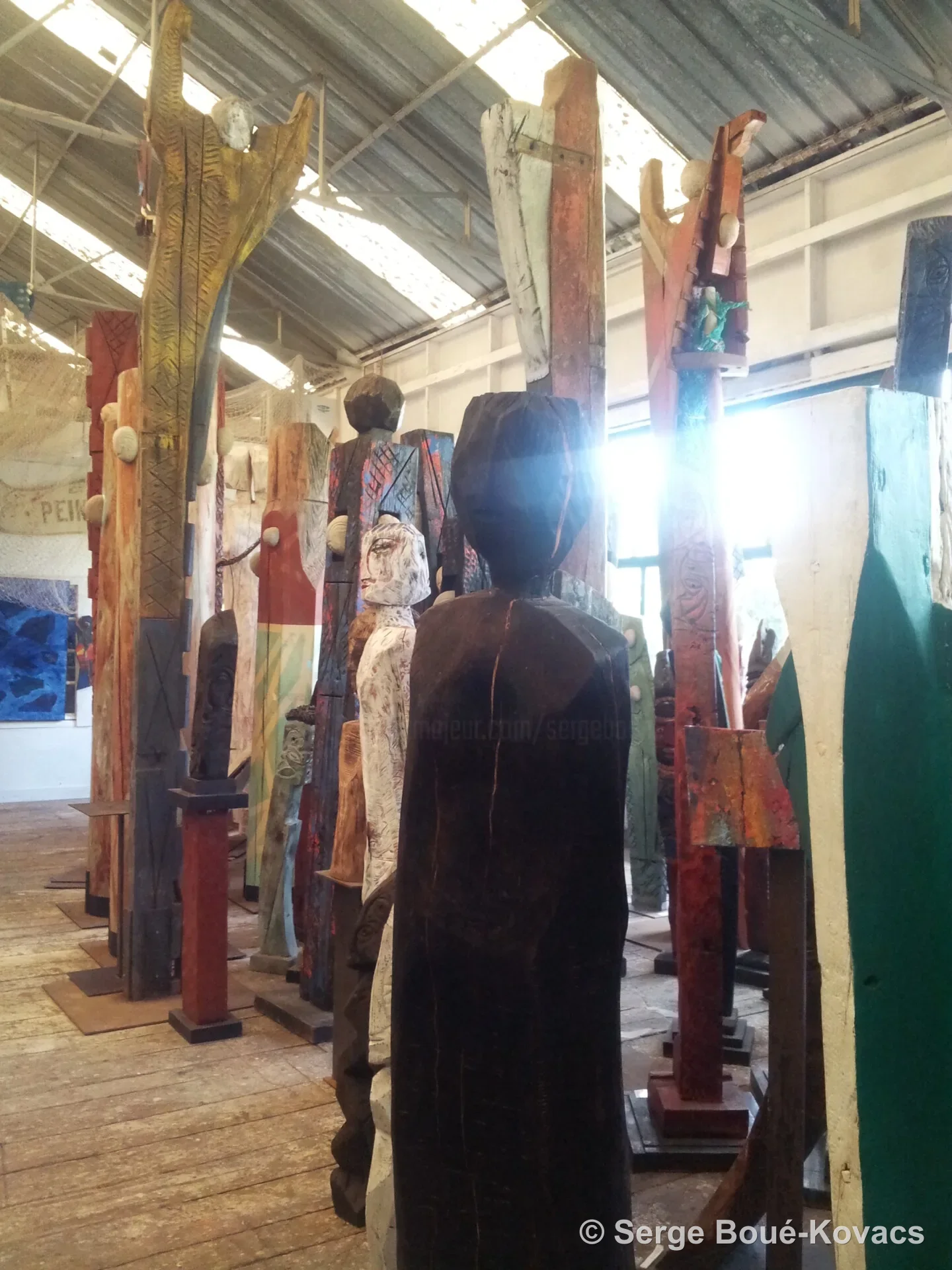 Silhouette noire parmi les totems — Sculpture de Serge Boué-Kovacs